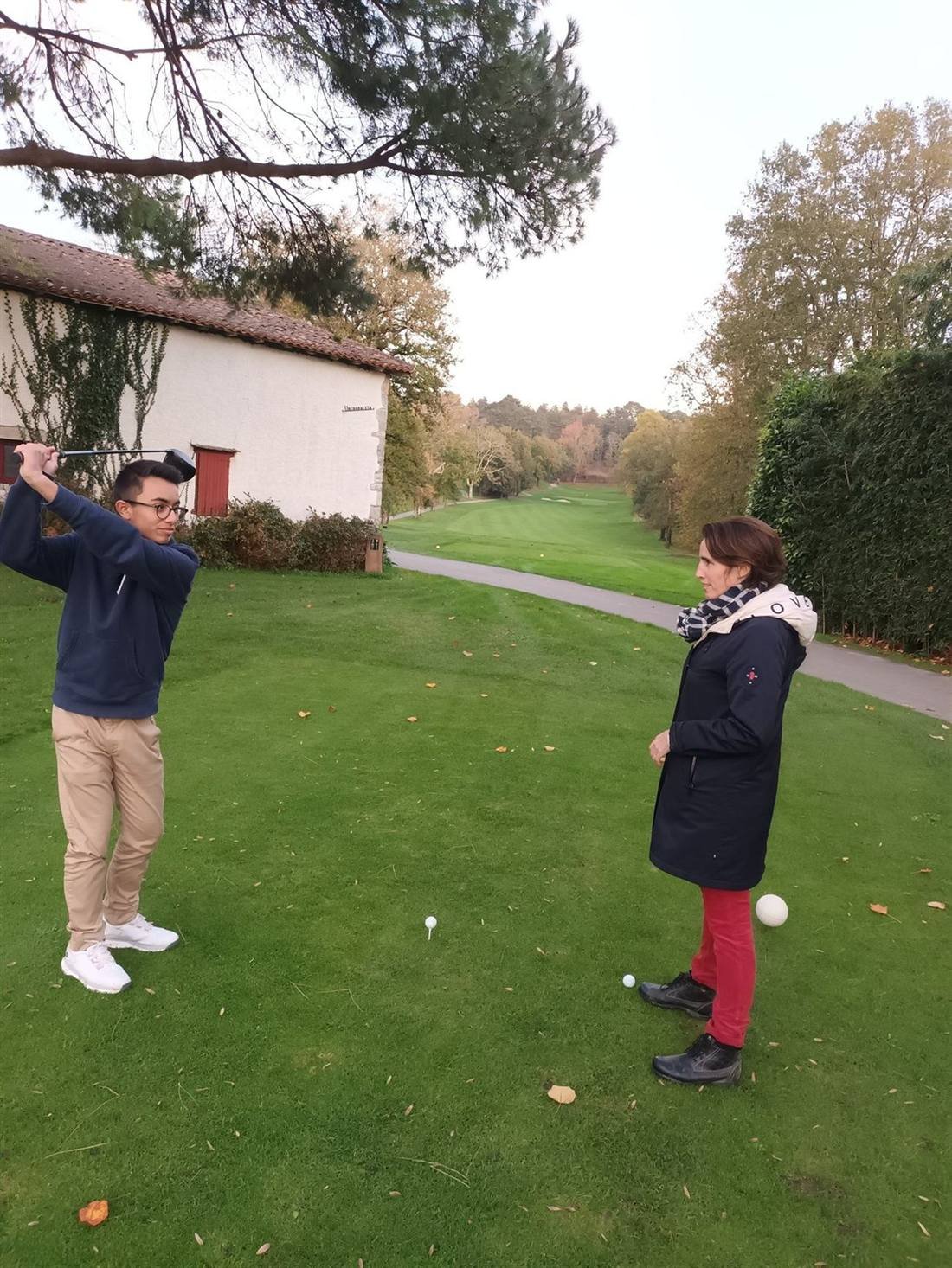 Sylvie sur le green avec un golfeur en plein swing — préparation mentale golf